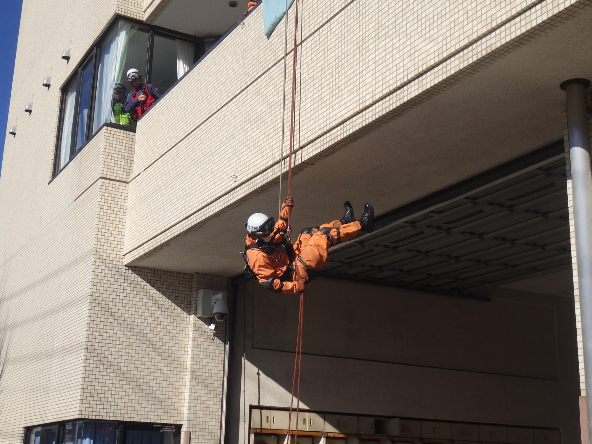 救助隊員がロープを使用し転落した作業員のいる1階屋根部分に降下して行きます。