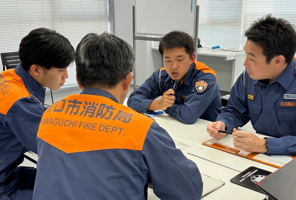 テーブルを囲んで4人の隊員が話し合っている写真