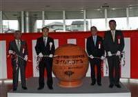 開封式典でタイムカプセルの横に立つ人々の写真