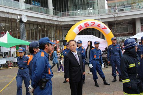 消防フェアで団員と話をする市長の写真