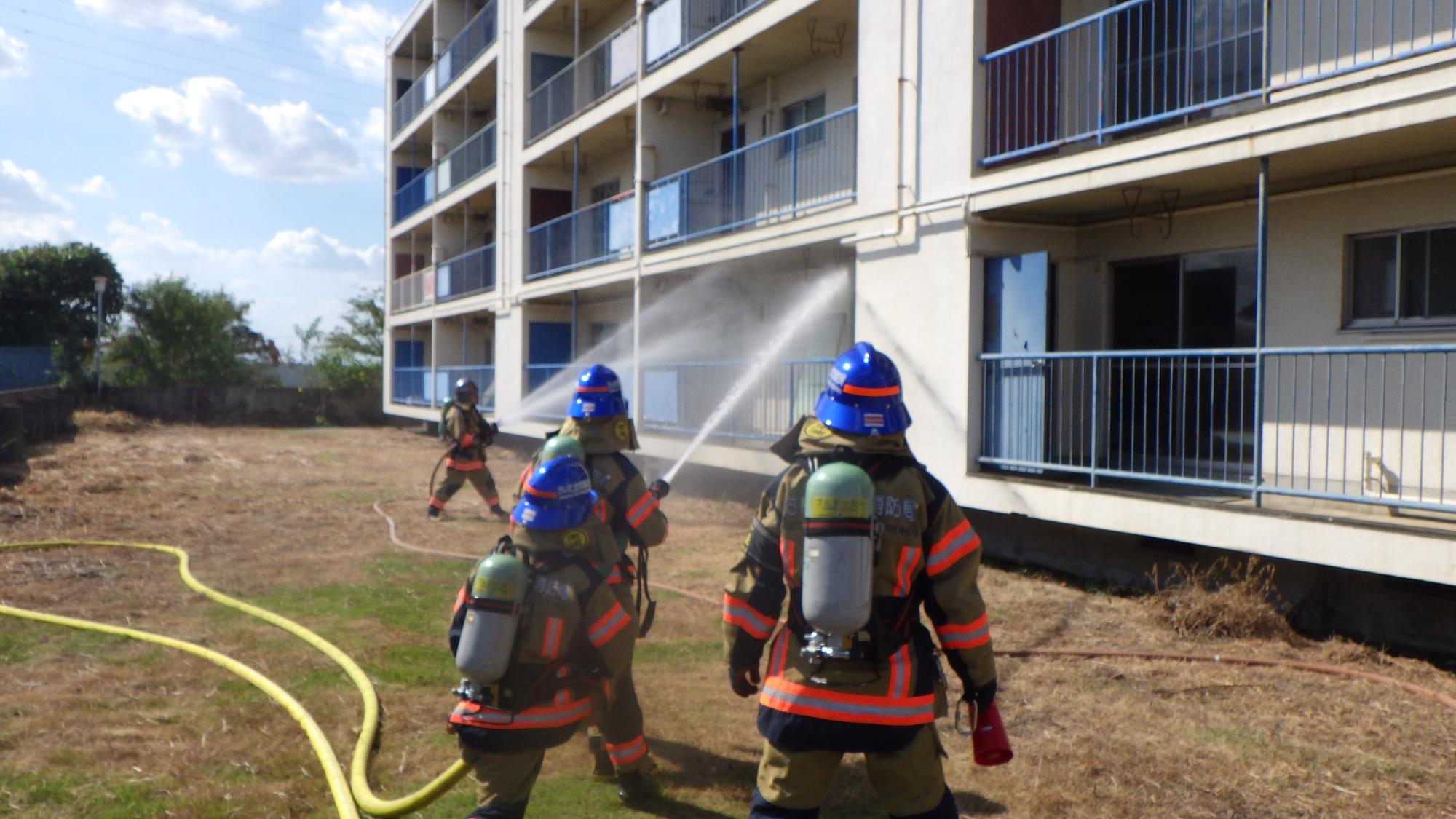 共同住宅のベランダ側に放水している様子