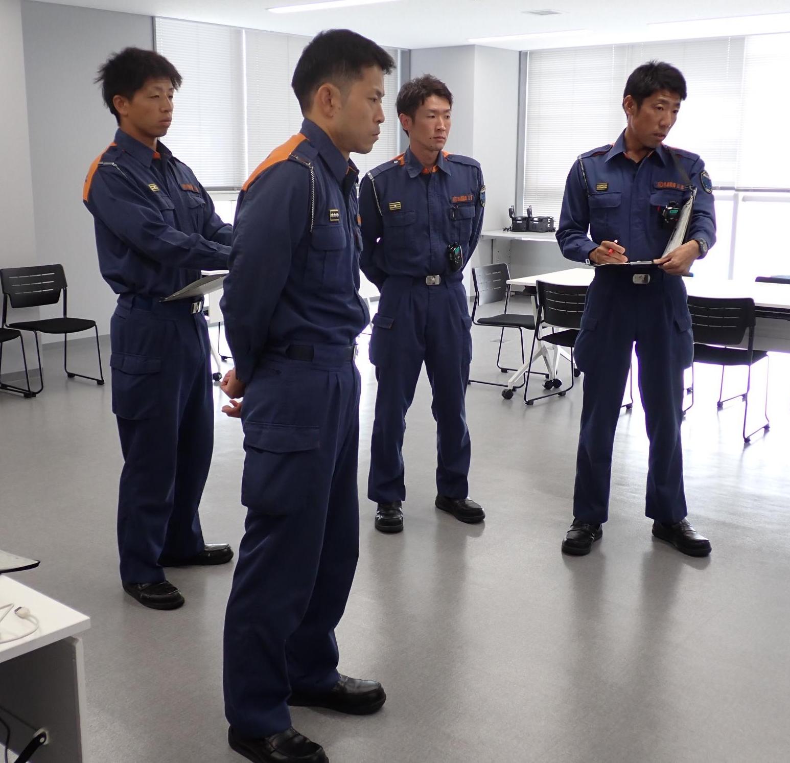 4人の消防隊員が立って、考えている写真。