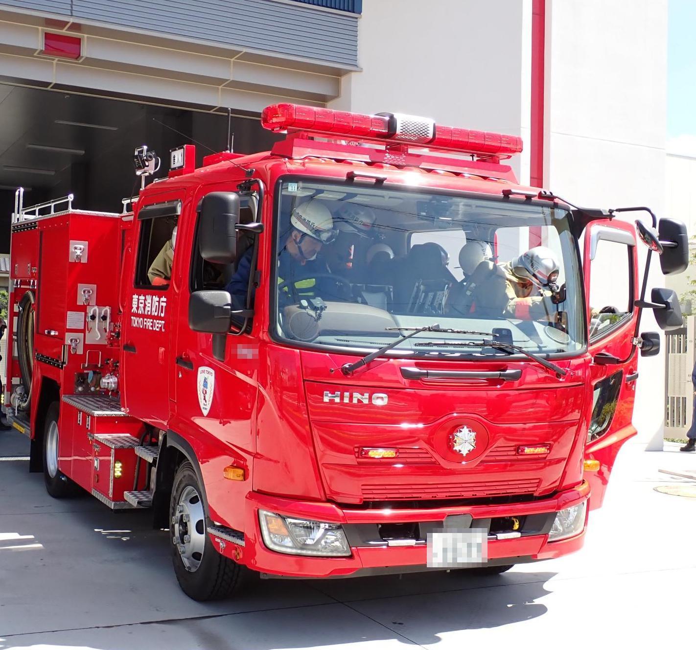 ドアに東京消防庁と書かれた消防車に運転手が座っており、助手席の隊員が乗りこんでいる写真