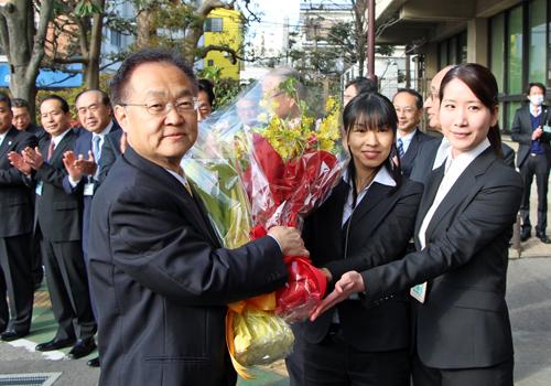 市役所前で花束を受け取る市長の写真