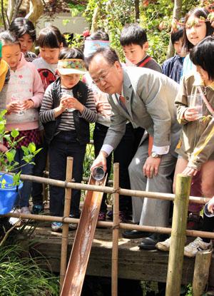 蛍の幼虫を放流する市長の写真